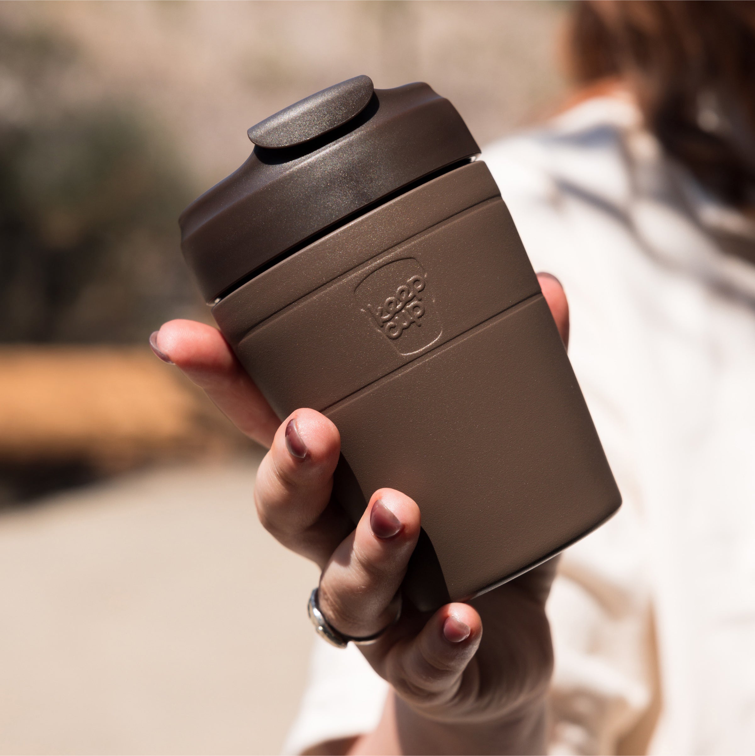 Hand holding a chocolate Brown Commuter travel mug in Chocolate