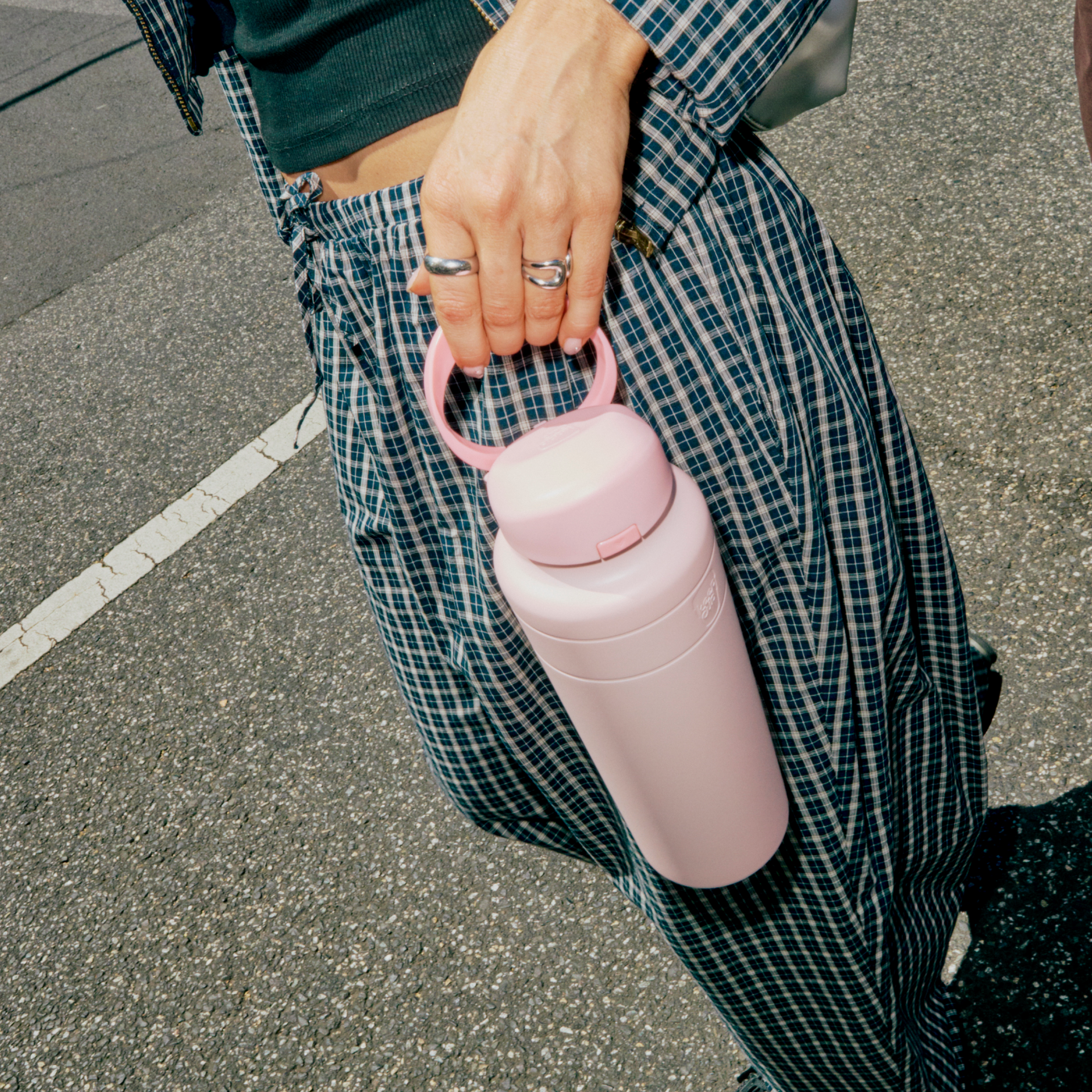 Person holding a pink water bottle with a checkered outfit