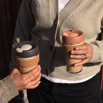 Person holding two KeepCup reusable coffee cups with different lid designs.
