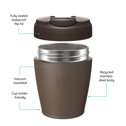A brown reusable KeepCup travel tumbler with its lid removed and floating above the cup, shown on a white background with callout lines and text describing features such as a sealed leakproof flip lid, vacuum insulation, recycled stainless steel body, and cup holder friendliness.