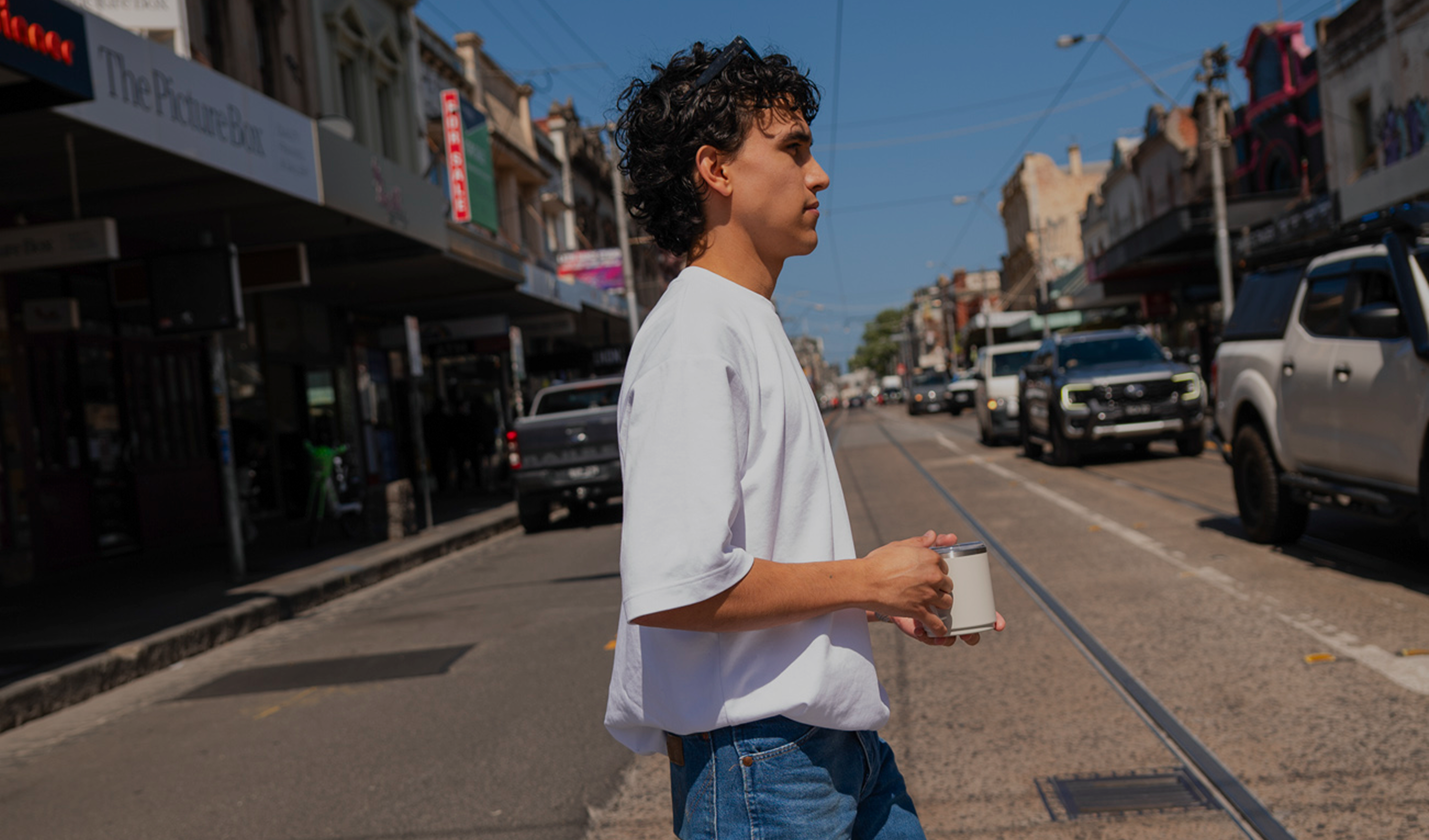 Person standing on a city street holding a coffee cup