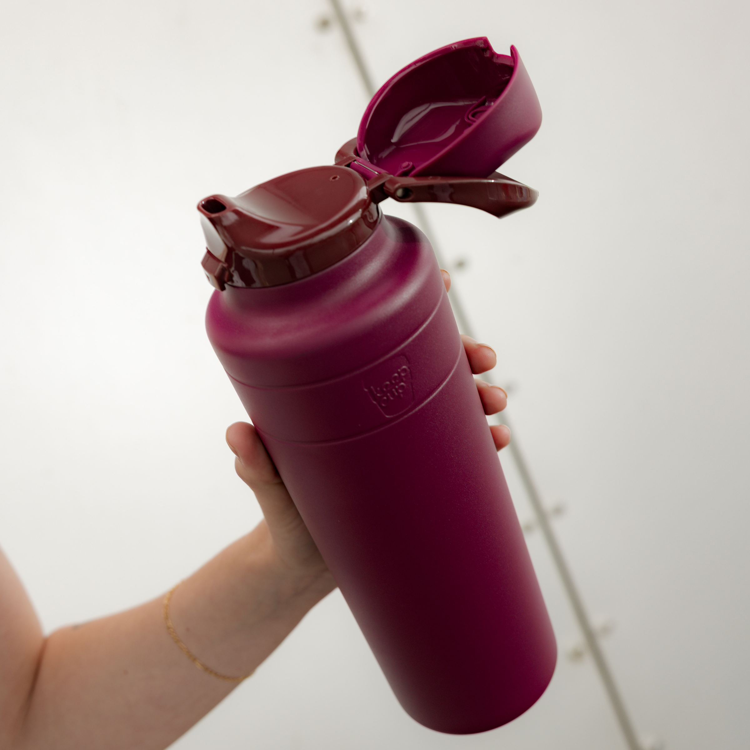 Hand holding a mulberry water bottle with a white background