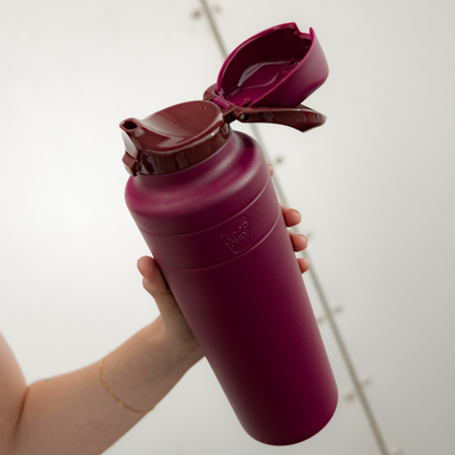 Hand holding a mulberry water bottle with a white background