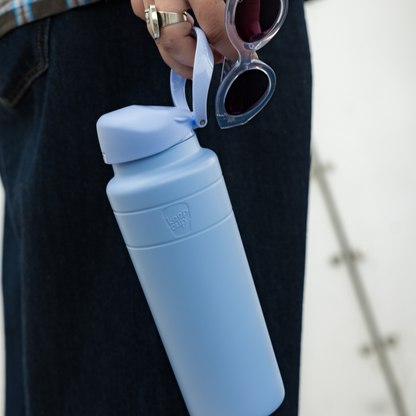 Orchid water bottle with a cap held by a person wearing dark pants.