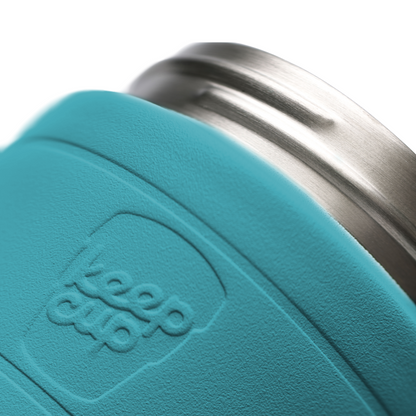Close-up of a teal insulated KeepCup tumbler with a brushed stainless steel rim, embossed with the KeepCup logo.