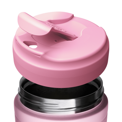 A close-up of a pink reusable KeepCup travel mug with a matching pink flip-straw lid shown partially removed, revealing the dark interior and stainless steel rim on a white background.