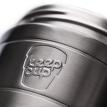 Close-up of a brushed stainless steel KeepCup insulated commuter travel mug with the embossed KeepCup logo on a white background.